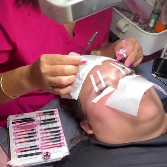 Trainer applying lashes on a model under the lash lamp